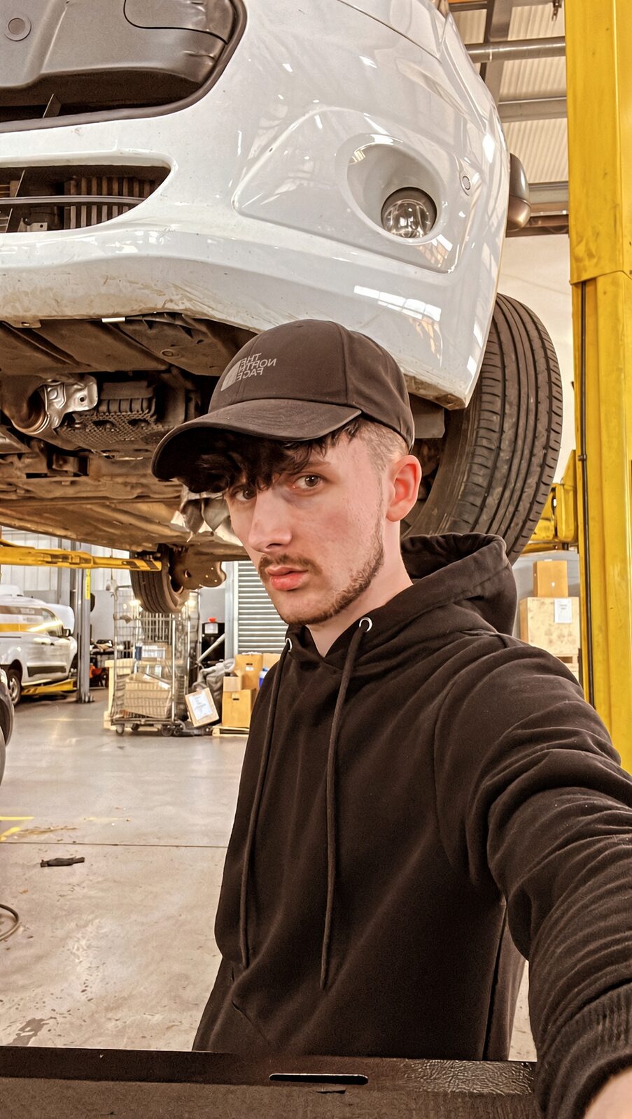 Jake Essex under a car on a lift at Ford in Upminster