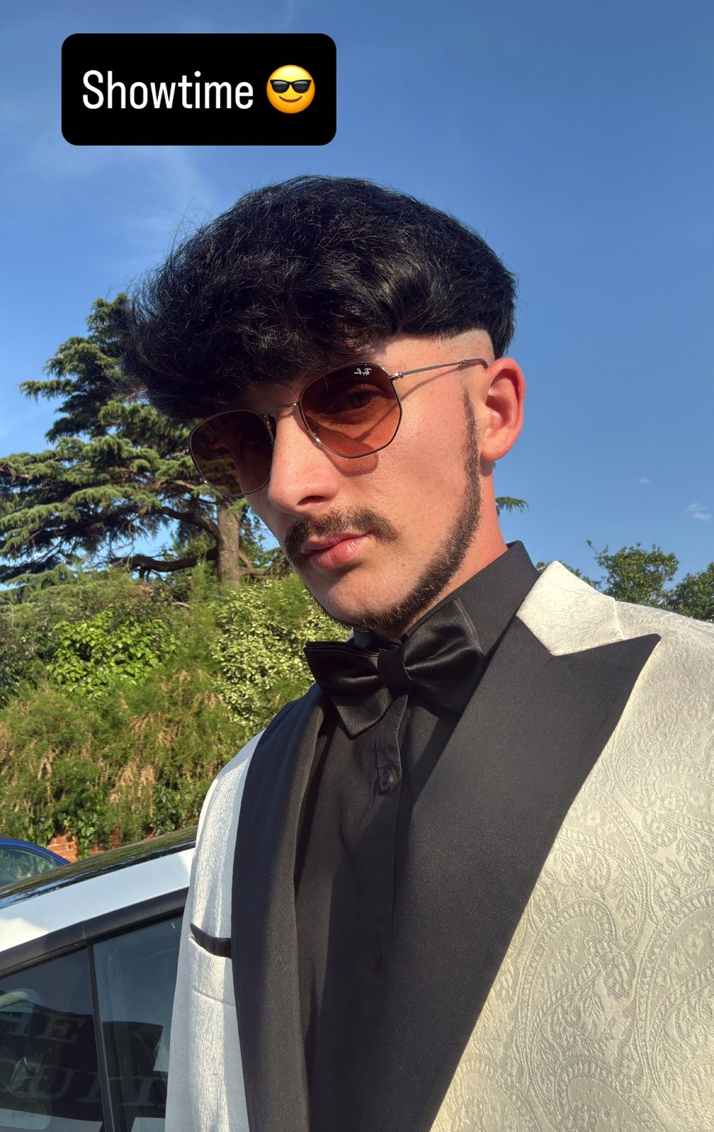 Jake Essex outdoors under a blue sky in a white dinner jacket