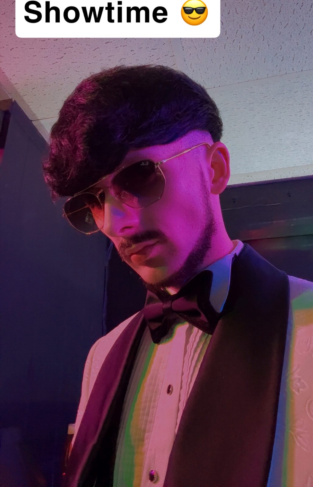 Jake Essex in a white dinner jacket under purple club lighting