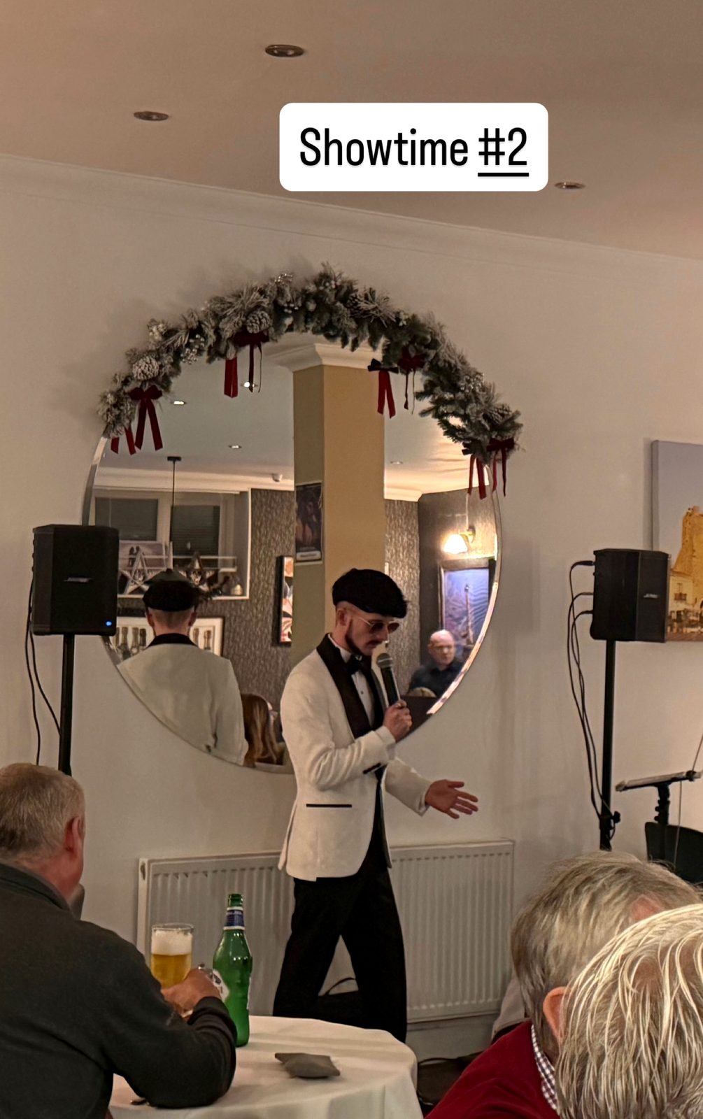 Jake Essex performing to a seated room, microphone in hand