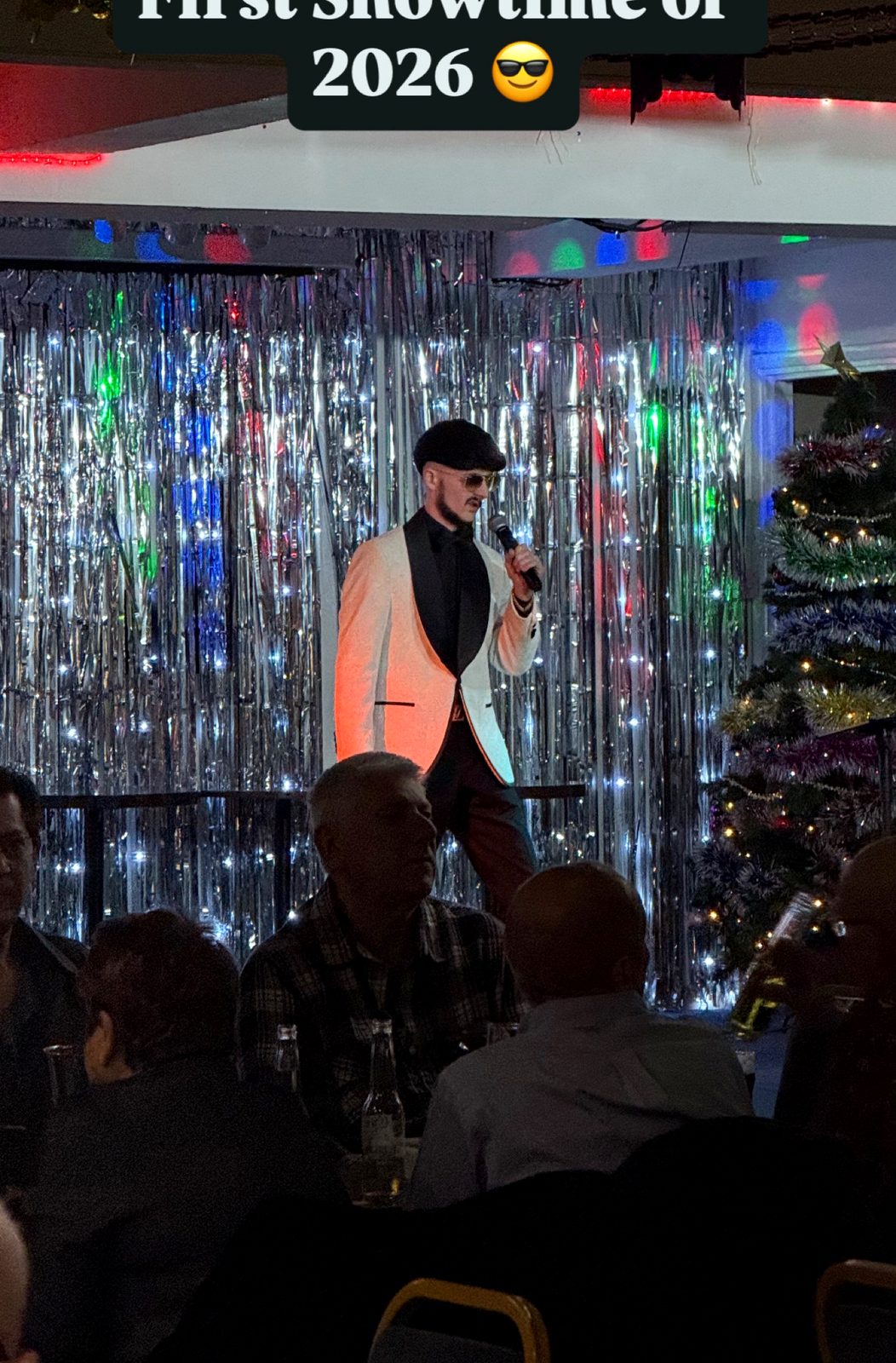 Jake Essex performing live in front of a silver tinsel curtain